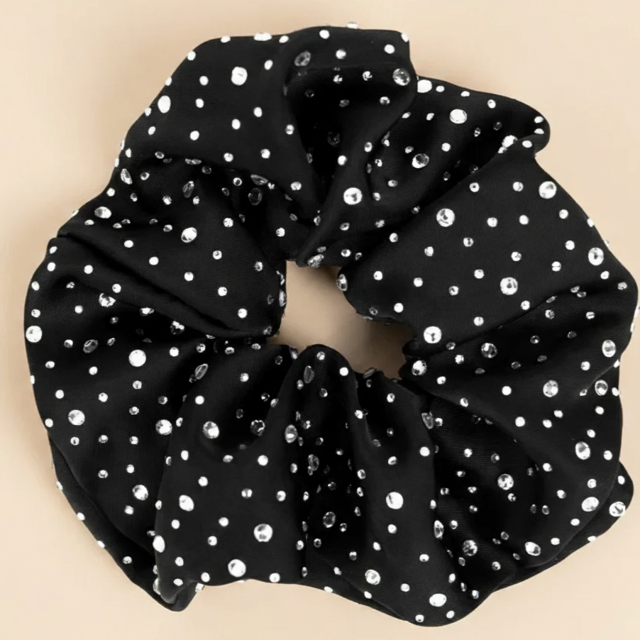 Black scrunchie with white polka dots on a beige background